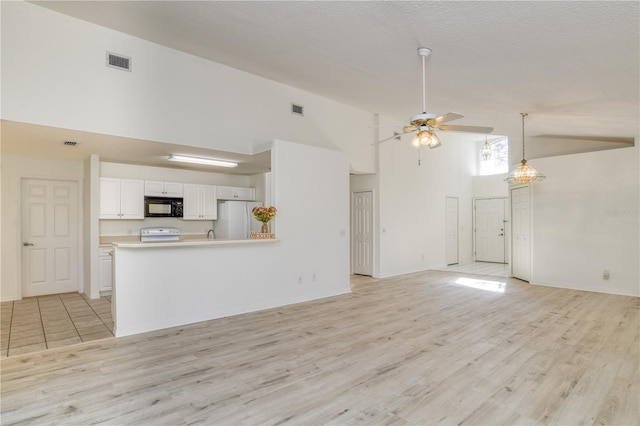 unfurnished living room featuring ceiling fan, high vaulted ceiling, a textured ceiling, and light wood-type flooring