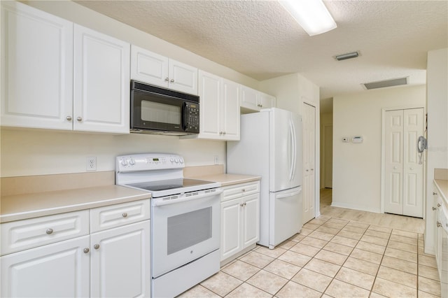 kitchen featuring a textured ceiling, light tile patterned floors, white cabinets, and white appliances