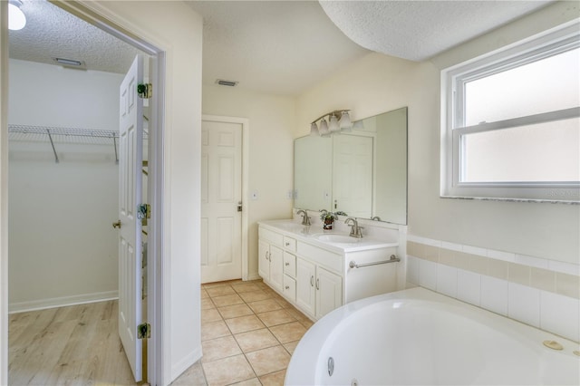 bathroom with tile patterned floors, a tub, vanity, and a textured ceiling