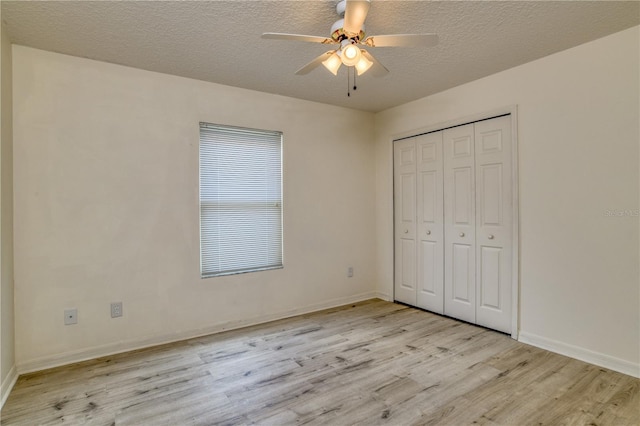 unfurnished bedroom with ceiling fan, light wood-type flooring, a textured ceiling, and a closet