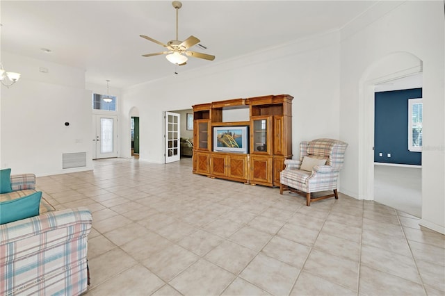 living room with light tile patterned flooring, ceiling fan with notable chandelier, and ornamental molding