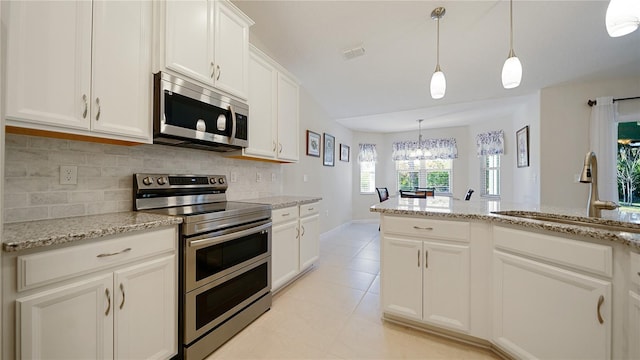 kitchen with backsplash, white cabinetry, stainless steel appliances, and decorative light fixtures