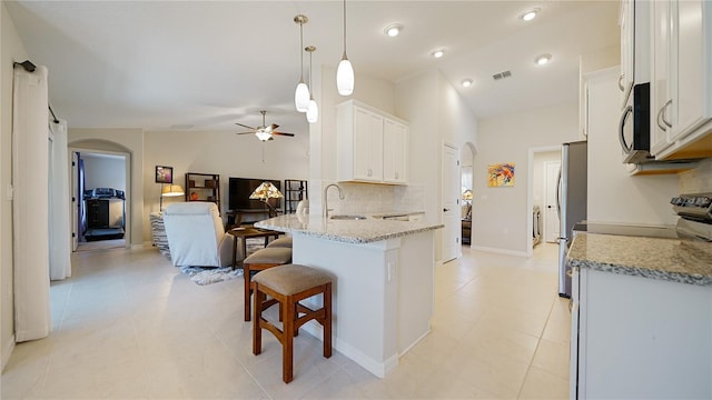 kitchen featuring kitchen peninsula, light stone counters, pendant lighting, white cabinets, and lofted ceiling