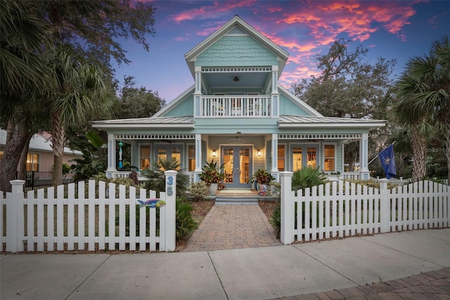 view of front of property with french doors, a balcony, and covered porch