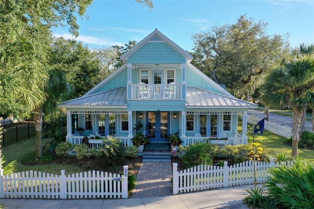 35 Smiling Fish Ln, Palm Coast, FL 32137 - victorian-style house featuring french doors, a porch, a standing seam roof, and a fenced front yard