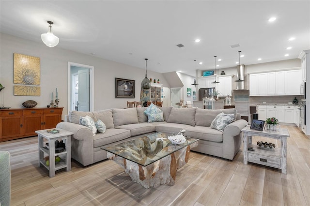 living room featuring light wood-style floors, recessed lighting, and visible vents