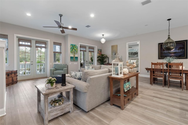 living area featuring visible vents, baseboards, french doors, light wood-type flooring, and recessed lighting