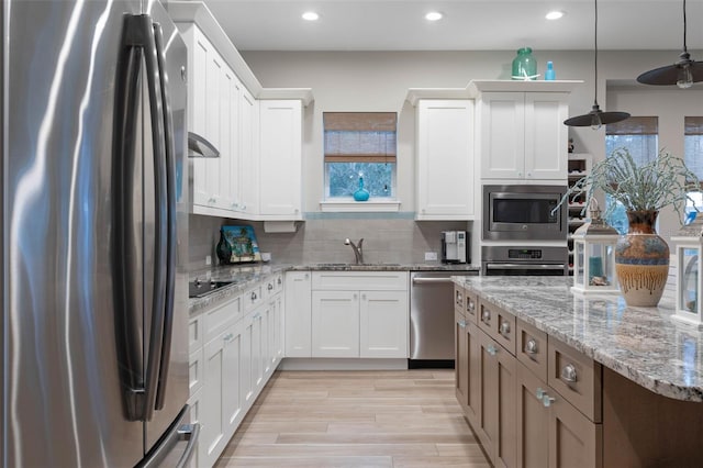 kitchen with recessed lighting, a sink, white cabinets, appliances with stainless steel finishes, and backsplash