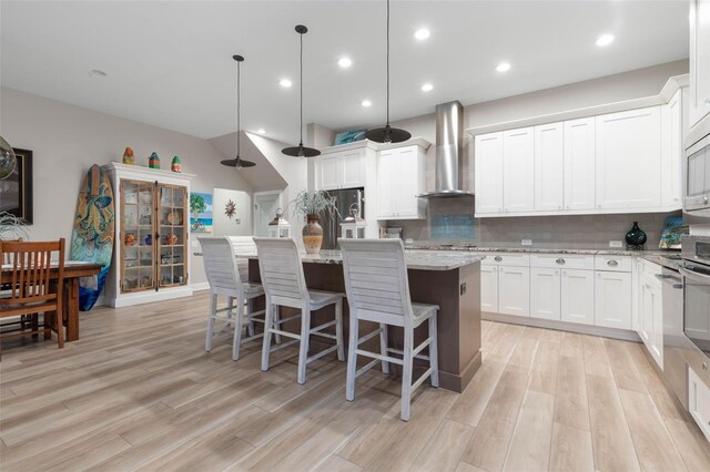 35 Smiling Fish Ln, Palm Coast, FL 32137 - kitchen featuring wall chimney exhaust hood, freestanding refrigerator, decorative backsplash, light wood finished floors, and recessed lighting