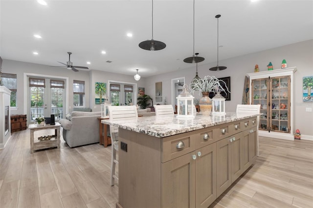 kitchen featuring light wood-style floors, french doors, a kitchen island, and a kitchen breakfast bar