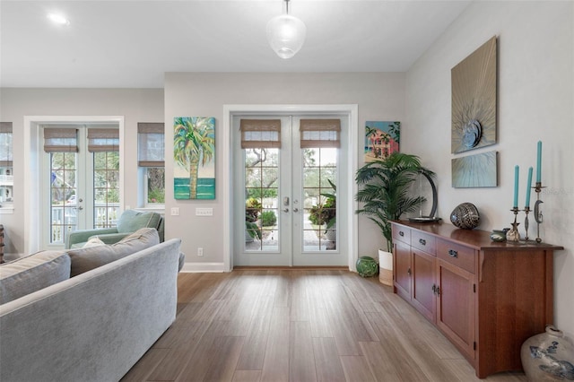 doorway to outside with french doors, baseboards, and light wood finished floors