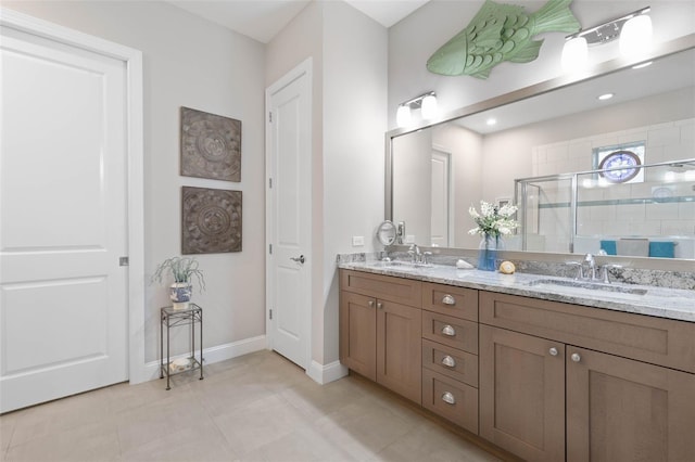 bathroom with baseboards, double vanity, a sink, and a shower stall