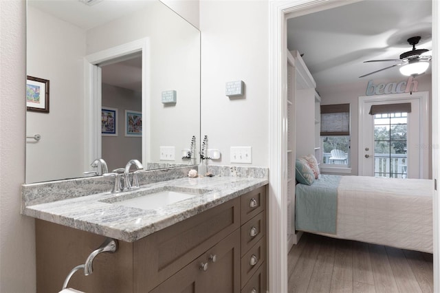 ensuite bathroom featuring ceiling fan, connected bathroom, a sink, and wood finished floors