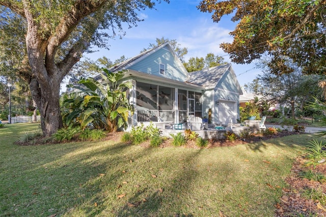 back of house with a lawn, an attached garage, and a sunroom