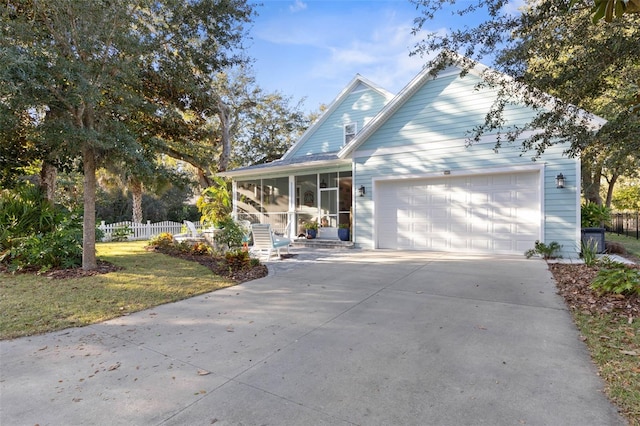 view of front of home with driveway, a sunroom, an attached garage, fence, and a front lawn