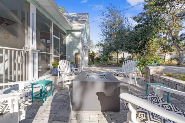 view of patio featuring an outdoor fire pit and a sunroom