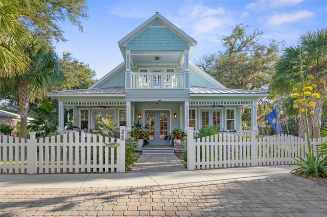 view of front of home with a fenced front yard, french doors, a porch, board and batten siding, and a balcony