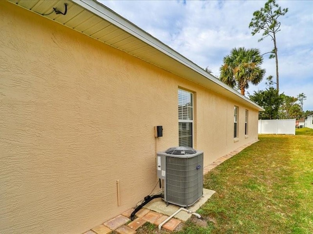 view of side of property with cooling unit and a lawn