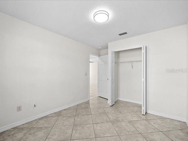 unfurnished bedroom with a closet, light tile patterned flooring, and a textured ceiling