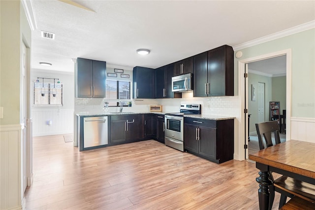 kitchen featuring light stone countertops, sink, stainless steel appliances, light hardwood / wood-style flooring, and decorative backsplash