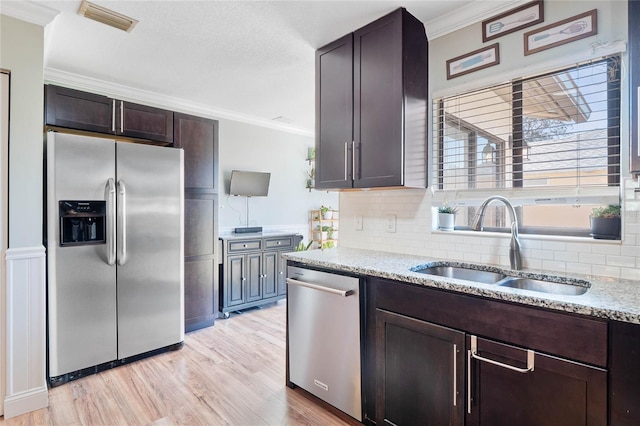 kitchen with sink, decorative backsplash, dark brown cabinets, appliances with stainless steel finishes, and ornamental molding