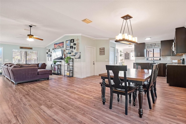 dining area featuring ceiling fan, light hardwood / wood-style flooring, vaulted ceiling, and ornamental molding