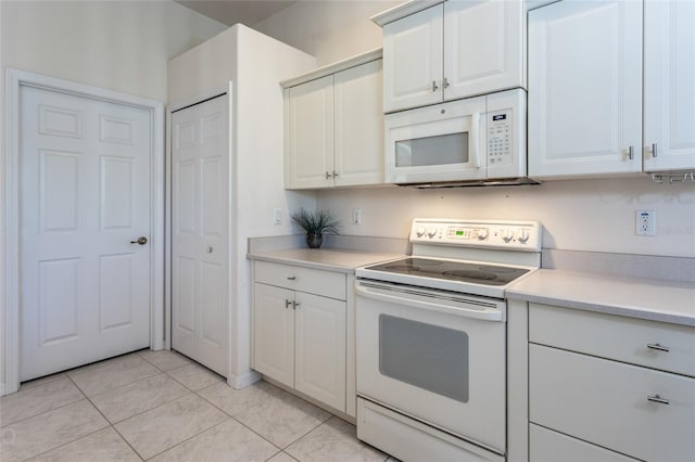 kitchen with light tile patterned floors, white appliances, and white cabinetry