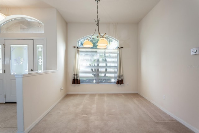 carpeted spare room featuring a chandelier