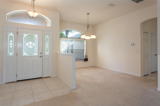 foyer entrance featuring light colored carpet and an inviting chandelier