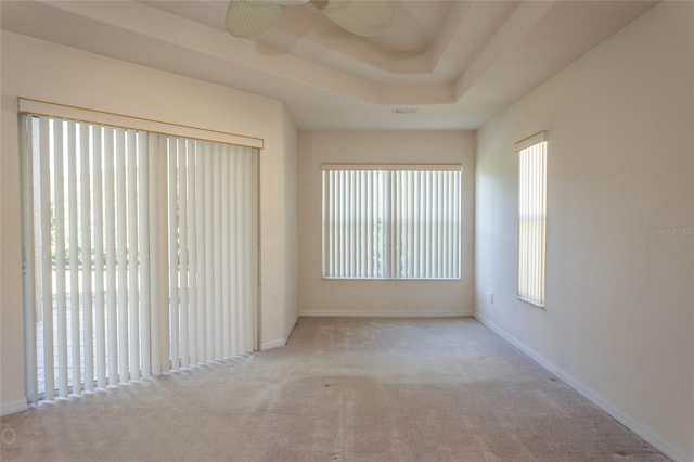 carpeted empty room featuring a tray ceiling and ceiling fan