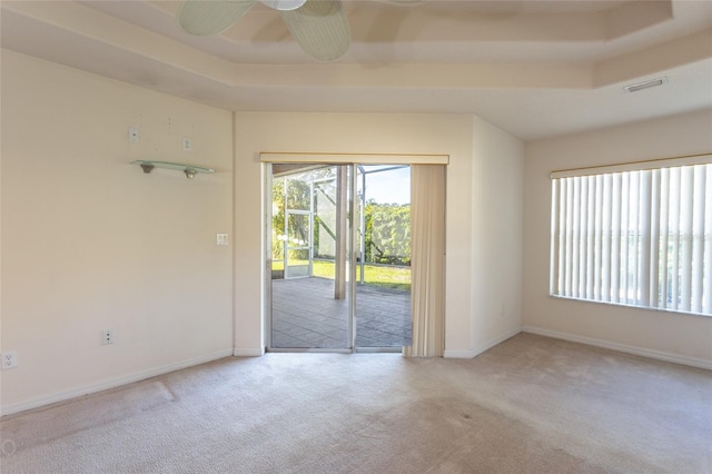 unfurnished room with light colored carpet, ceiling fan, and a tray ceiling