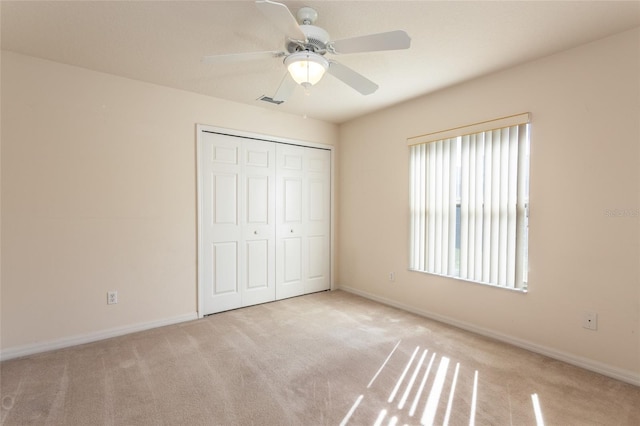 unfurnished bedroom with a closet, ceiling fan, and light colored carpet