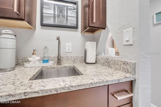 kitchen featuring light stone counters and sink