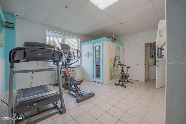 workout room featuring a paneled ceiling and light tile patterned floors