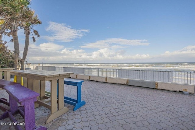 view of patio / terrace with a beach view and a water view