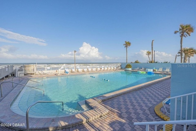 view of pool featuring a water view and a patio