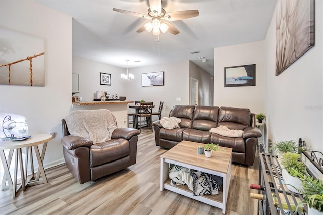 living room featuring ceiling fan with notable chandelier and light wood-type flooring