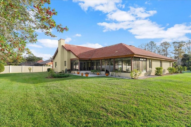 rear view of house with a lawn and a sunroom