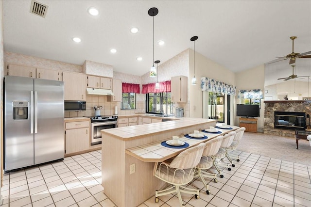 kitchen featuring kitchen peninsula, appliances with stainless steel finishes, vaulted ceiling, decorative light fixtures, and tile counters