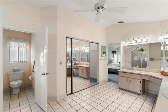 bathroom featuring a textured ceiling, a wealth of natural light, ceiling fan, and vaulted ceiling