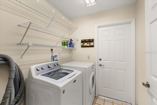 clothes washing area featuring separate washer and dryer and light tile patterned floors