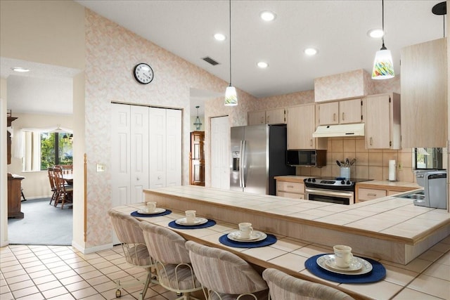 kitchen featuring light carpet, appliances with stainless steel finishes, tile countertops, and decorative light fixtures