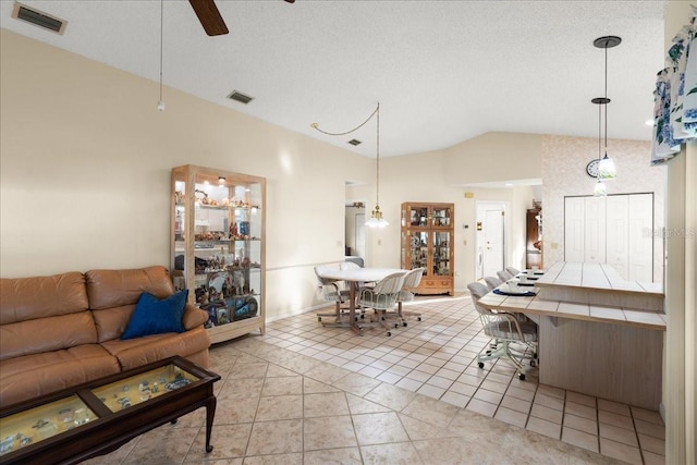 tiled living room with a textured ceiling, ceiling fan, and vaulted ceiling