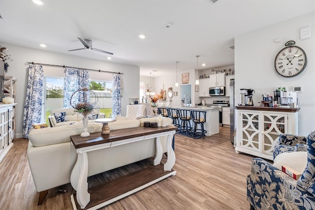 living room with ceiling fan, light hardwood / wood-style floors, and sink