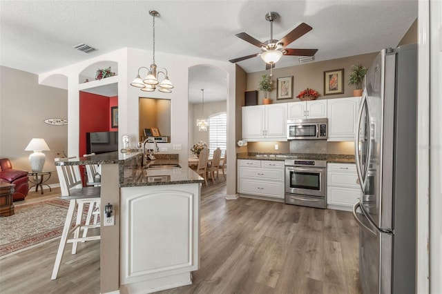 kitchen with white cabinetry, stainless steel appliances, kitchen peninsula, pendant lighting, and a textured ceiling