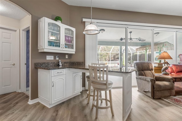 kitchen featuring white cabinets, a kitchen breakfast bar, light hardwood / wood-style flooring, and hanging light fixtures