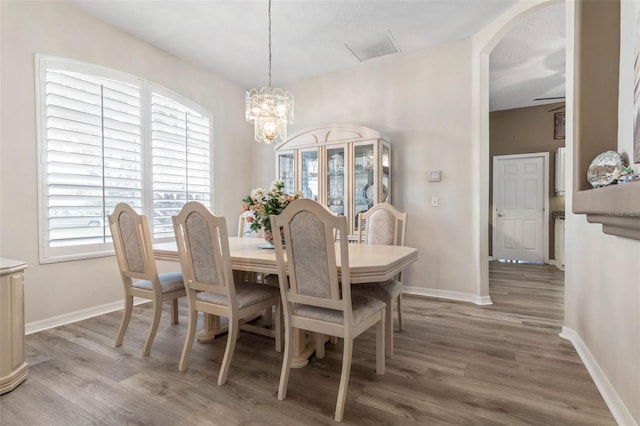 dining area featuring ceiling fan with notable chandelier and hardwood / wood-style flooring