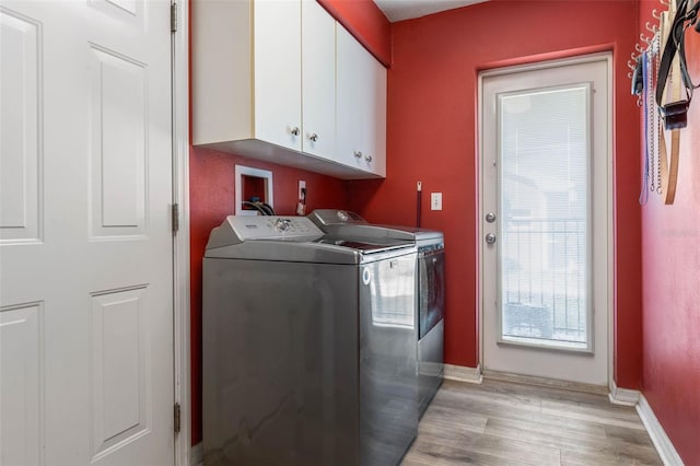 laundry room featuring cabinets, light hardwood / wood-style floors, and independent washer and dryer