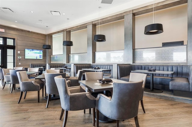 dining space with light hardwood / wood-style flooring and wood walls