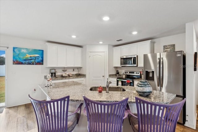 kitchen with sink, white cabinets, light wood-type flooring, and appliances with stainless steel finishes